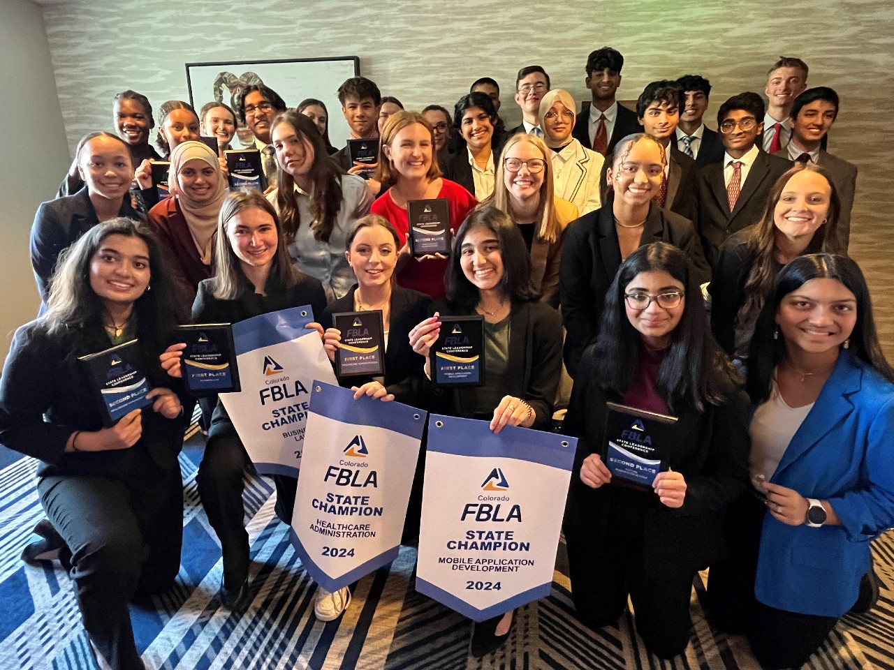 FBLA group posing together with their State Champion banners and plaques